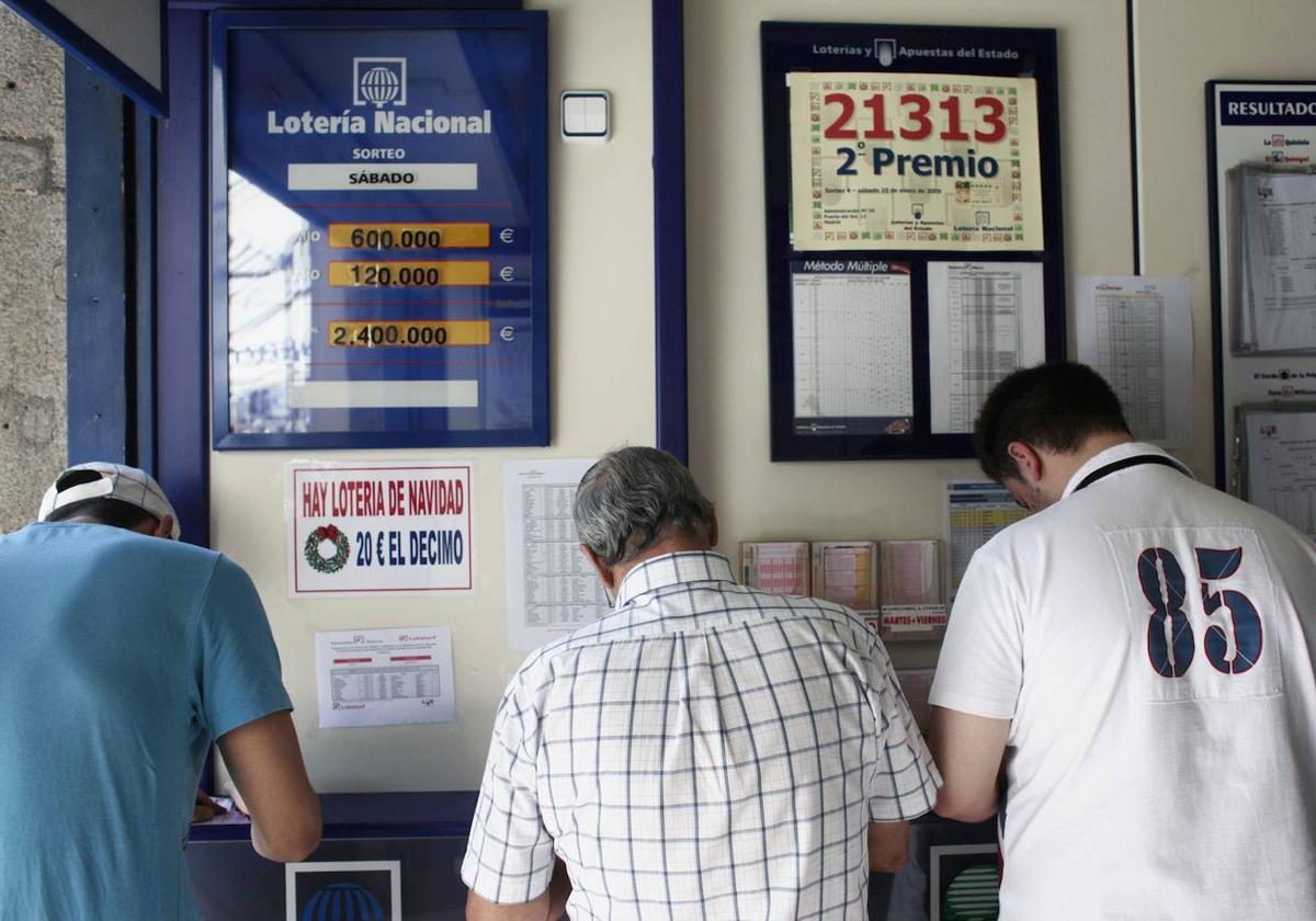 Varias personas realizan sus apuestas en una administración de Lotería.