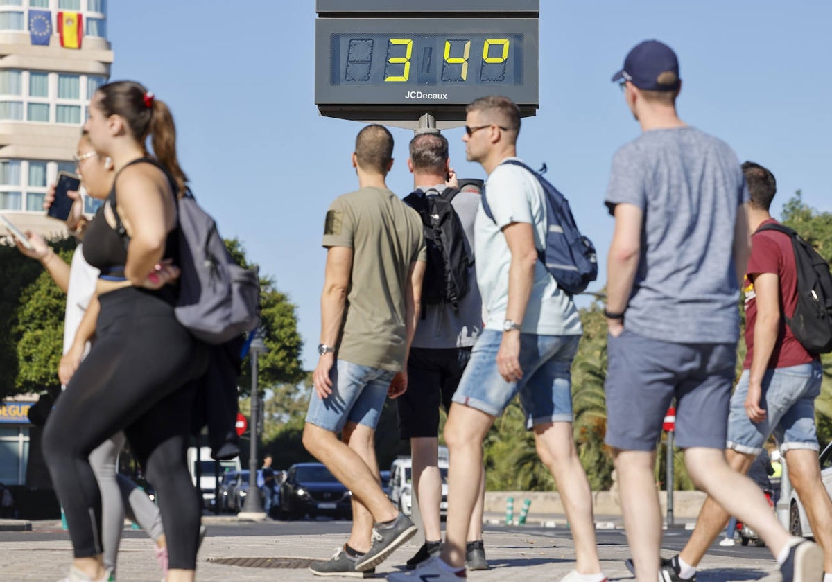 Unos turistas pasan por delante de un termómetro.