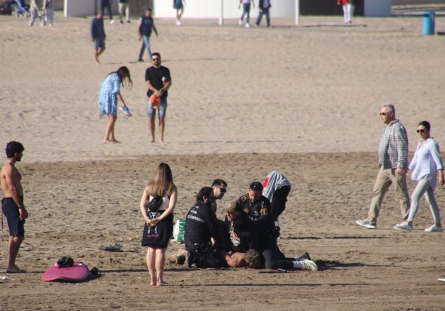 Los policías inmovilizan al individuo en la arena.