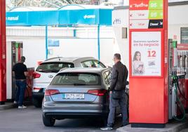 Dos conductores repostan combustible en una gasolinera.