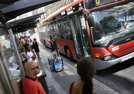 Varias personas aguardan en la parada de un autobús de la EMT en el centro de Valencia.