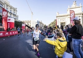 Una corredora recibe los ánimos de unos niños en el Maratón.