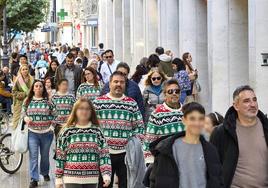 Un grupo de personas camina por la calle Colón con el mismo jersey navideño.