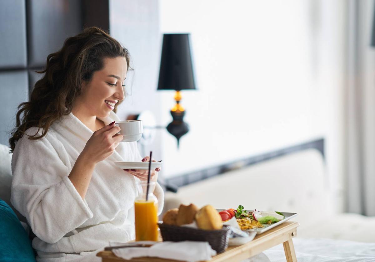 Una mujer se toma el desayuno en la cama.