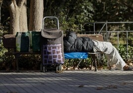 Una persona sin hogar durmiendo en un banco.