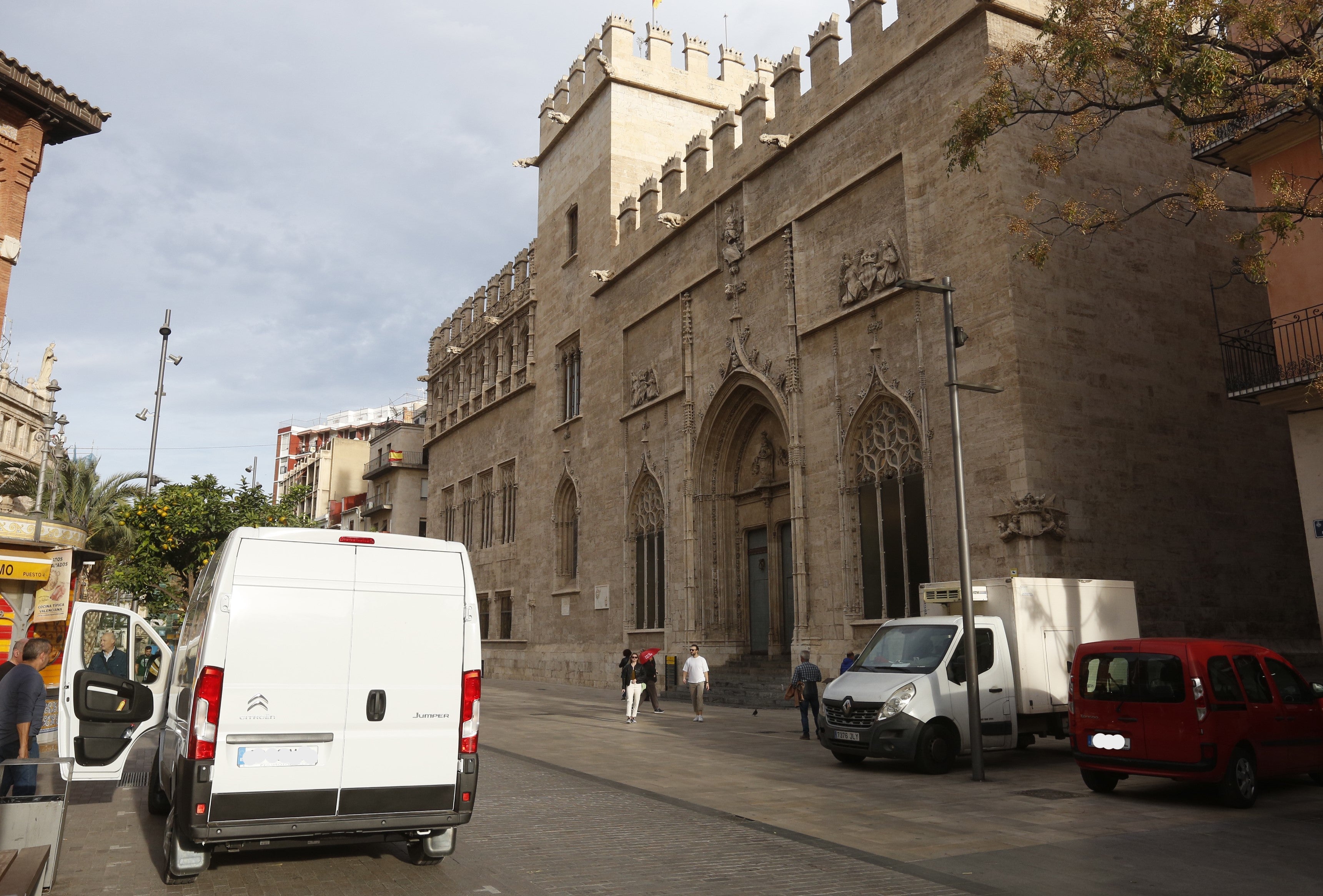 Vehículos estacionados mientras cargan y descargan genero en el entorno protegido de la Lonja.