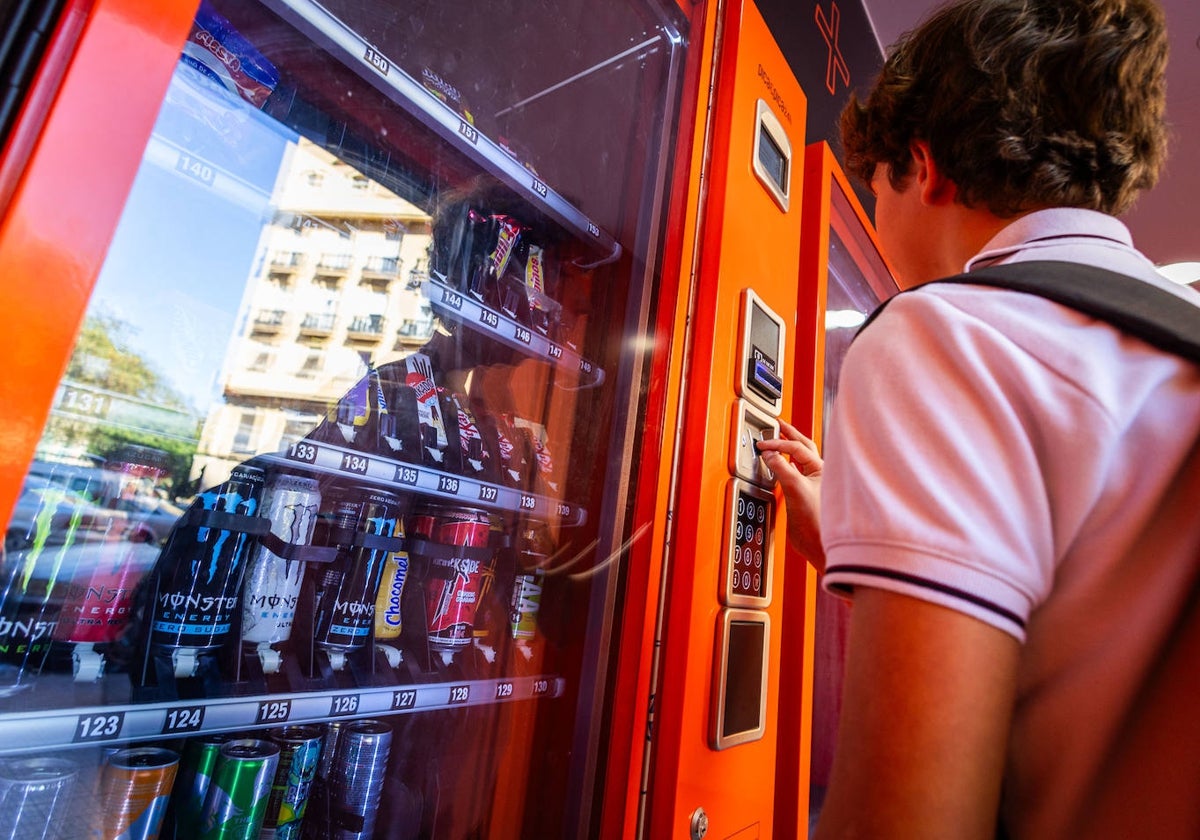 Un menor comprando bebidas energéticas en una máquina.