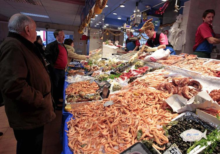 Varias personas comprando marisco en un mercado para estas navidades.