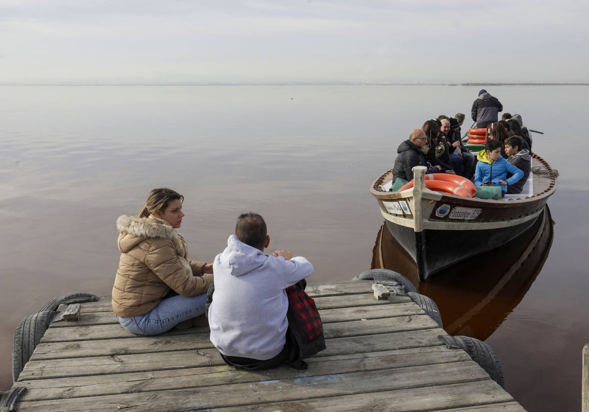 Unos turistas esperan para dar un paseo en barca por la Albufera.