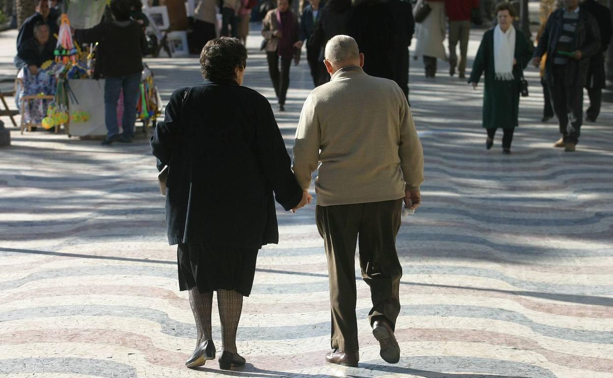 Dos señores pasean de la mano por la ciudad