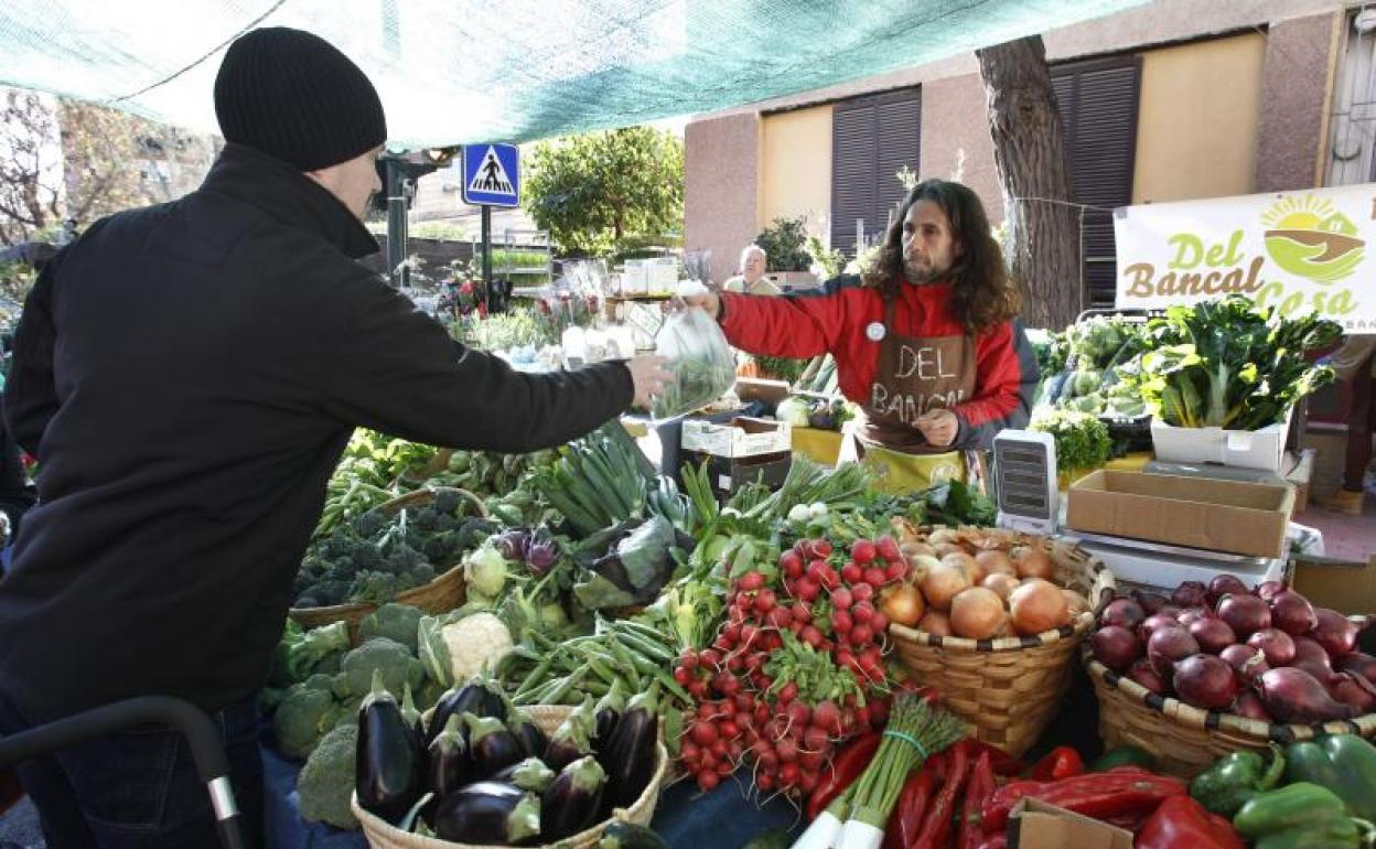 Un vendedor atiende a un cliente en un mercado de verduras. 