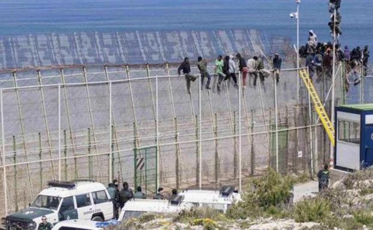 Inmigrantes encaramados a la valla de Melilla, en una imagen de archivo.