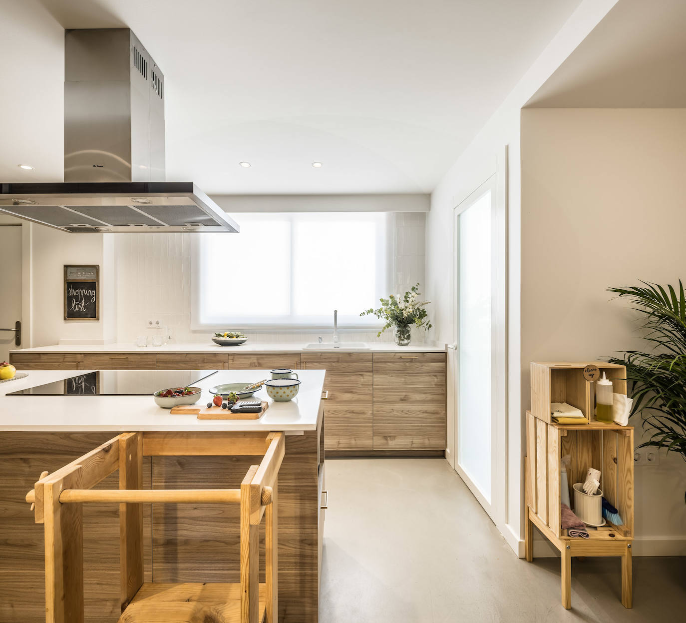 La cocina cuenta con una isla donde está ubicada la encimera y una gran campana. 