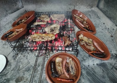 Imagen secundaria 1 - El gerente de Ca Juan de Daimús con dos bocadillos gigantes, una parrillada de carne y el clásico 'cremaet' con el que se acaban los almuerzos en la Safor. 