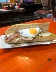 Imagen secundaria 2 - Una empleada sirve dos bocadillos, una cazuela de all i pebre y otro tipo de bocata. 