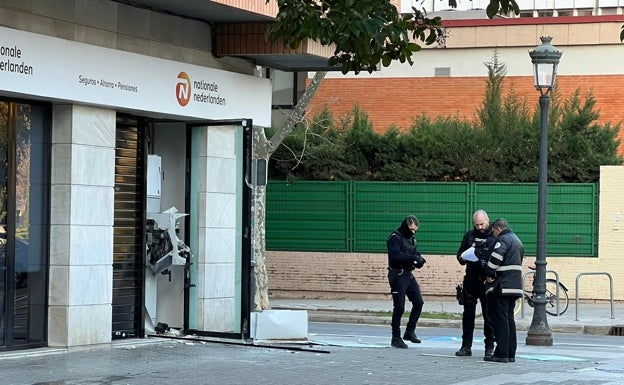 Dos policías y un vigilante custodian la puerta de la sucursal. 