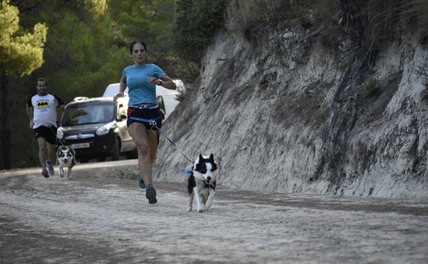 Una corredora, en primer plano, junto a su perro en una competición. 