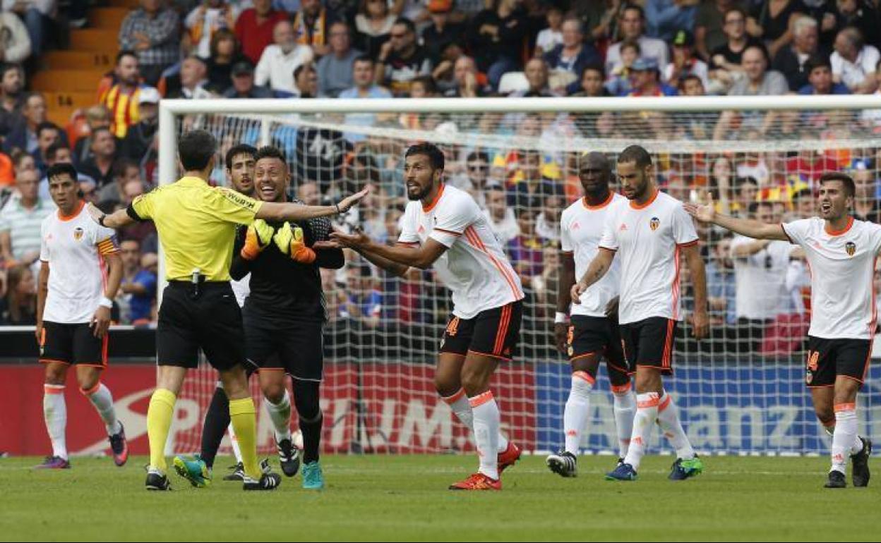 Los jugadores del Valencia protestan ante el árbitro Undiano Mallenco el gol de Messi en fuera de juego posicional de Súarez, en octubre de 2016.