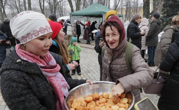 Una mujer kazaja distribuye baursaki, un pan tradicional de su país, a los lugareños cerca de una de las yurtas instaladas en el centro de Kiev para atender a la población. 