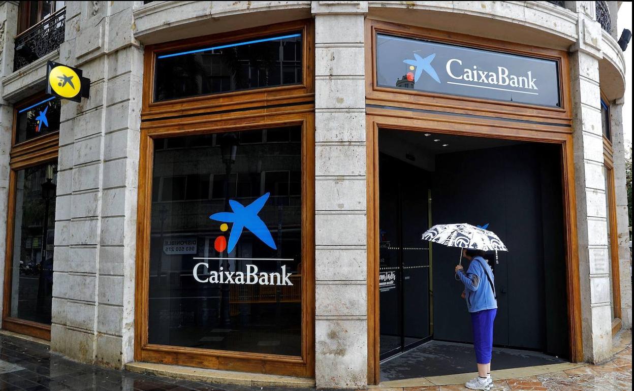 Una mujer observa el interior de la sede de Caixabank.