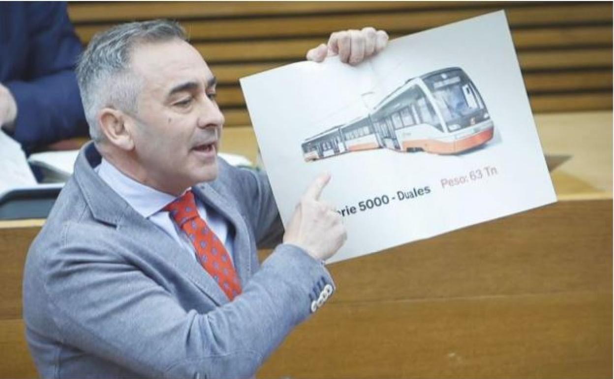 Miguel Barrachina, portavoz adjunto del Grupo Popular en Les Corts, muestra el modelo usado en la Línea 9 del Tram durante el debate en Les Corts. 