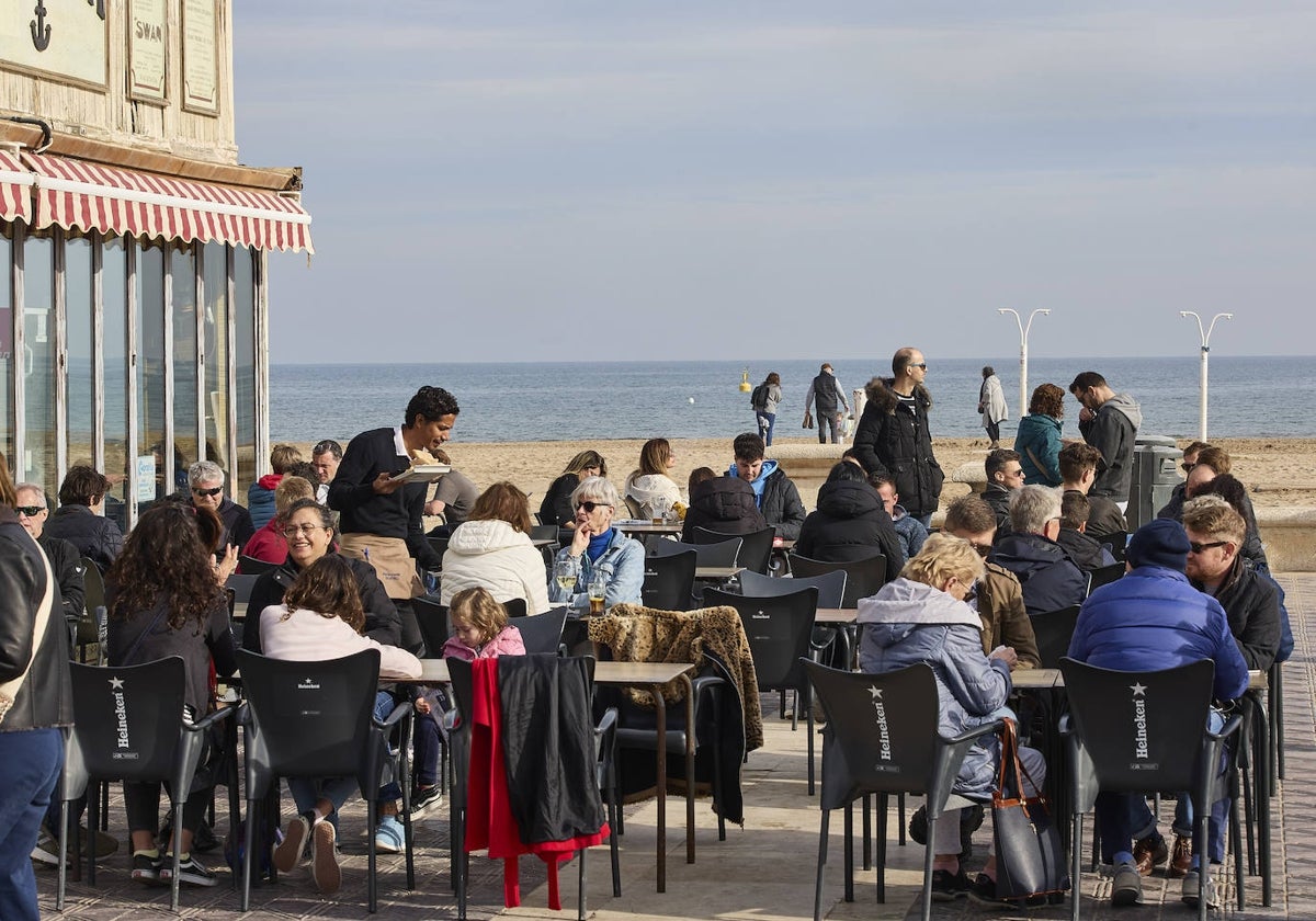 Turistas disfrutan de la terraza en la playa de la Malvarrosa.