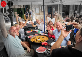 Un grupo de turistas se fotografía junto a una paella de marisco en un restaurante de Valencia.