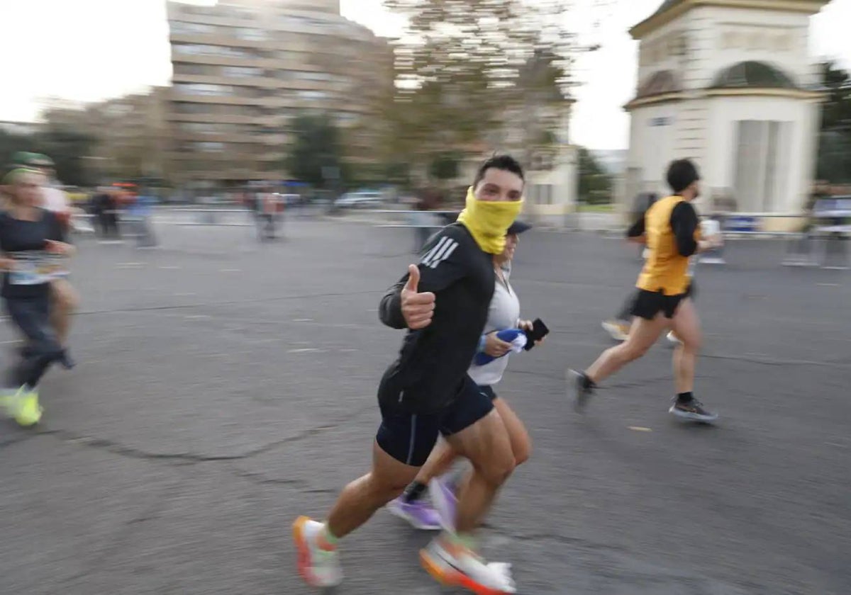 Un participante de la 10K Valencia Ibercaja 2024, cubriéndose para evitar el frío.