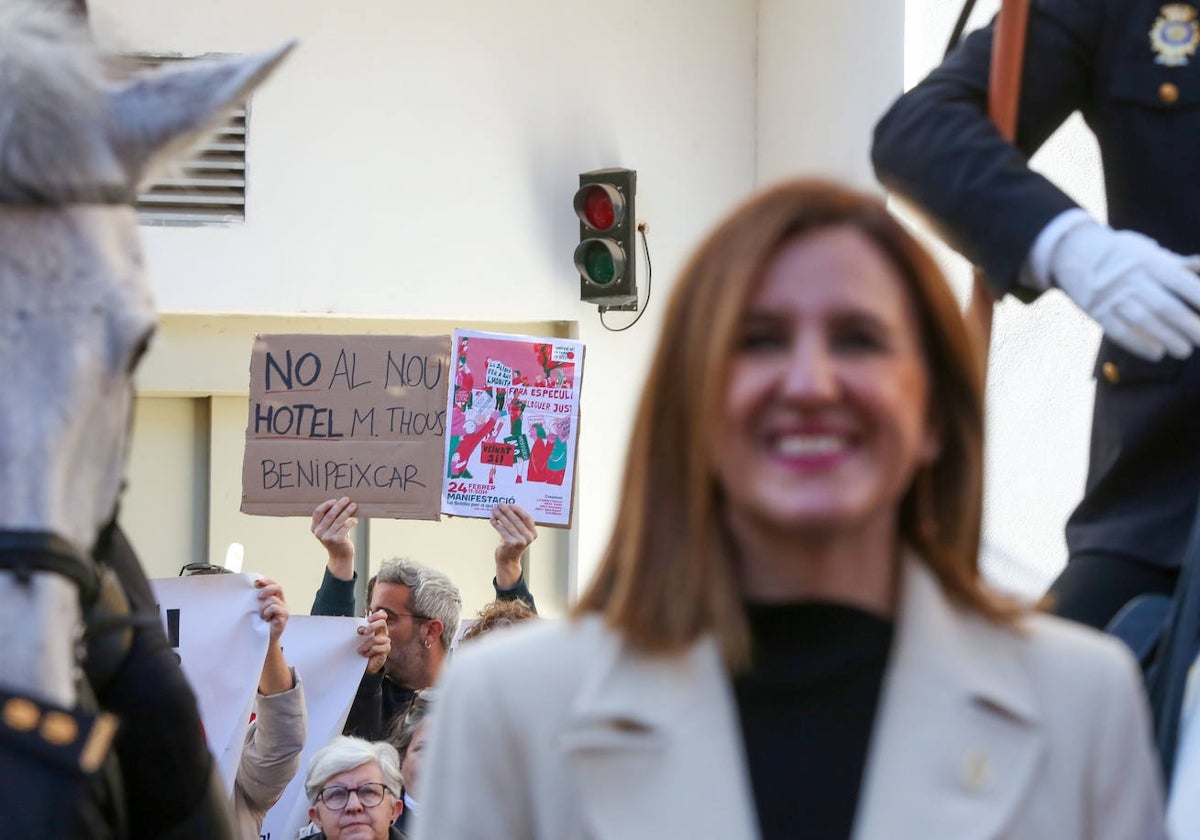 La alcaldesa de Valencia, María José Catalá, y en el fondo, protesta de vecinos de Zaidía.