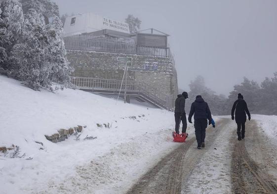 Varias personas arrastran un trineo en el Puerto de Navacerrada este viernes.