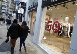 Dos jóvenes pasan por delante del escaparate de una de las tiendas de la calle Colón.