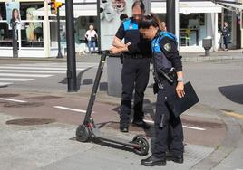 Dos policías inspeccionan un patinete.