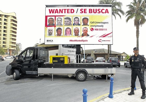 Un policía frente a una pantalla donde figuran fotografías de fugitivos.