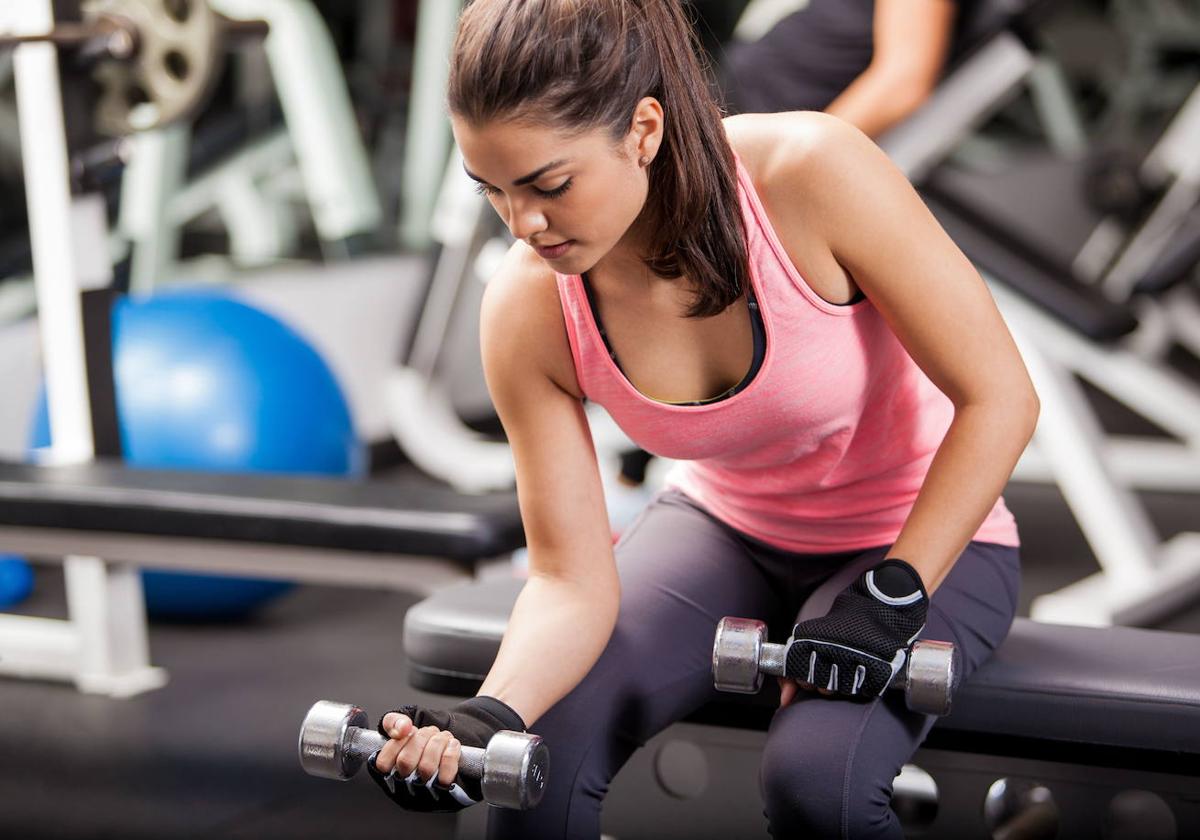 Una mujer levanta pesas en un gimnasio.