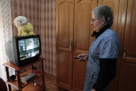 Una mujer intenta sintonizar el televisor.