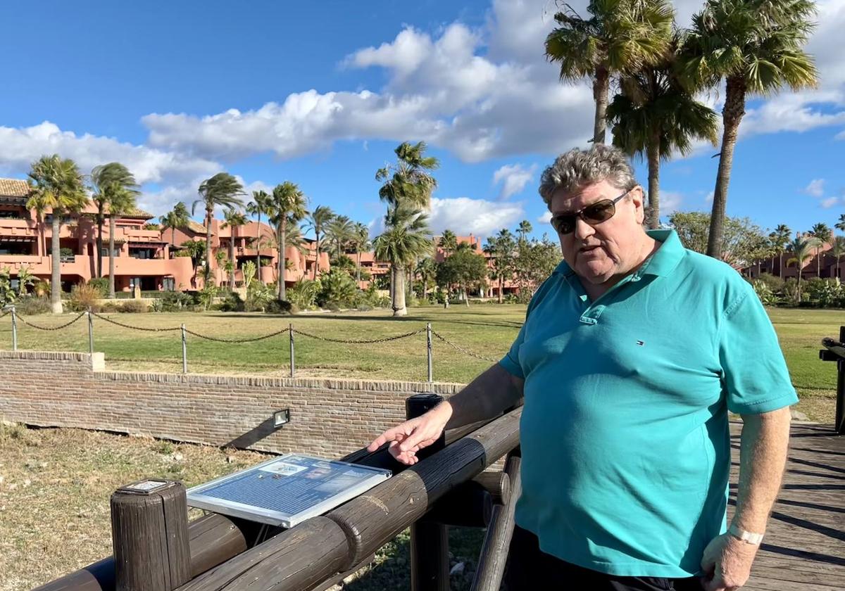 Arwyn Powell, presidente de la Entidad Urbanística de Conservación Guadalmansa, en Estepona (Málaga), señala un cartel de la urbanización donde los vecinos han denunciado al presidente.