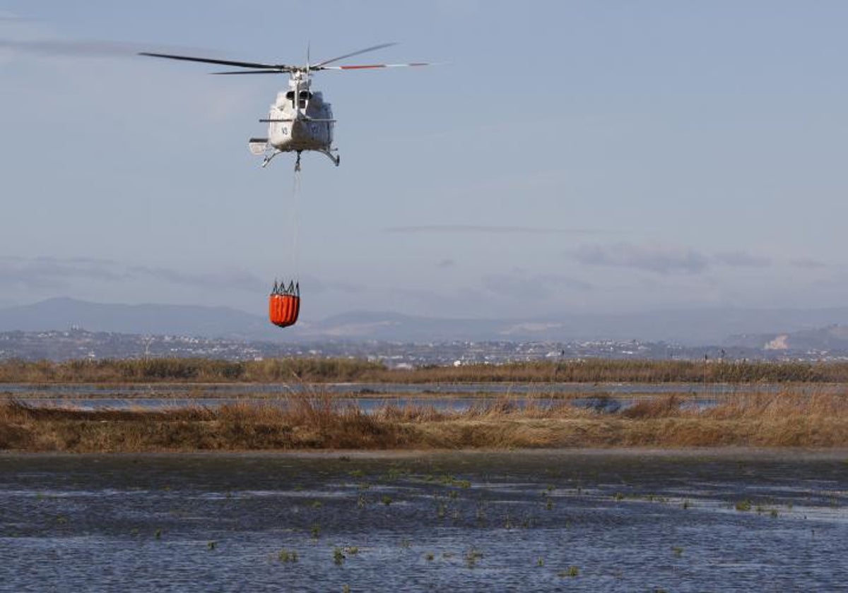 Un helicóptero carga agua en el lago, este martes.