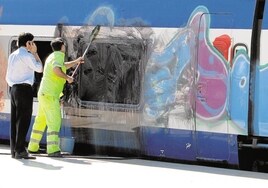 Unos operarios de Renfe limpian un tren con grafitis.