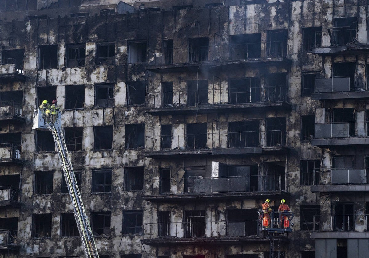 Bomberos revisan la fachada del edificio, completamente arrasada por el devastador fuego.