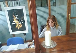 Una trabajadora del centro, en la entrada, junto a una vela por las víctimas y un cartel que expresa el luto de la comunidad docente.