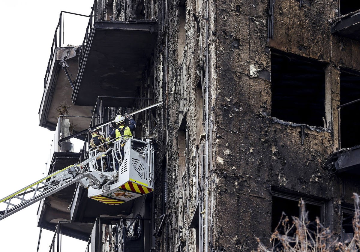 Dos bomberos revisan una de las fachadas quemadas, este lunes.