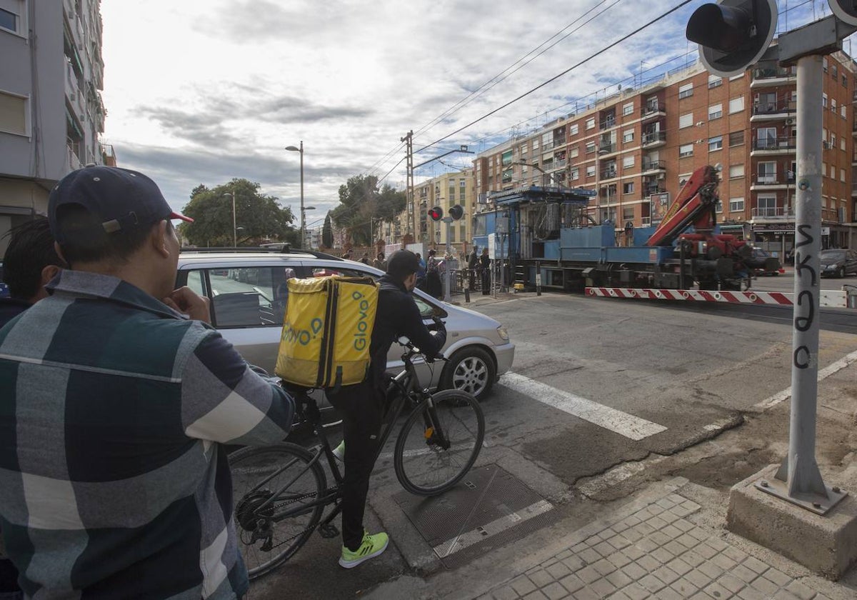 Peatones y vehículos esperan para cruzar en el paso a nivel de Alfafar.