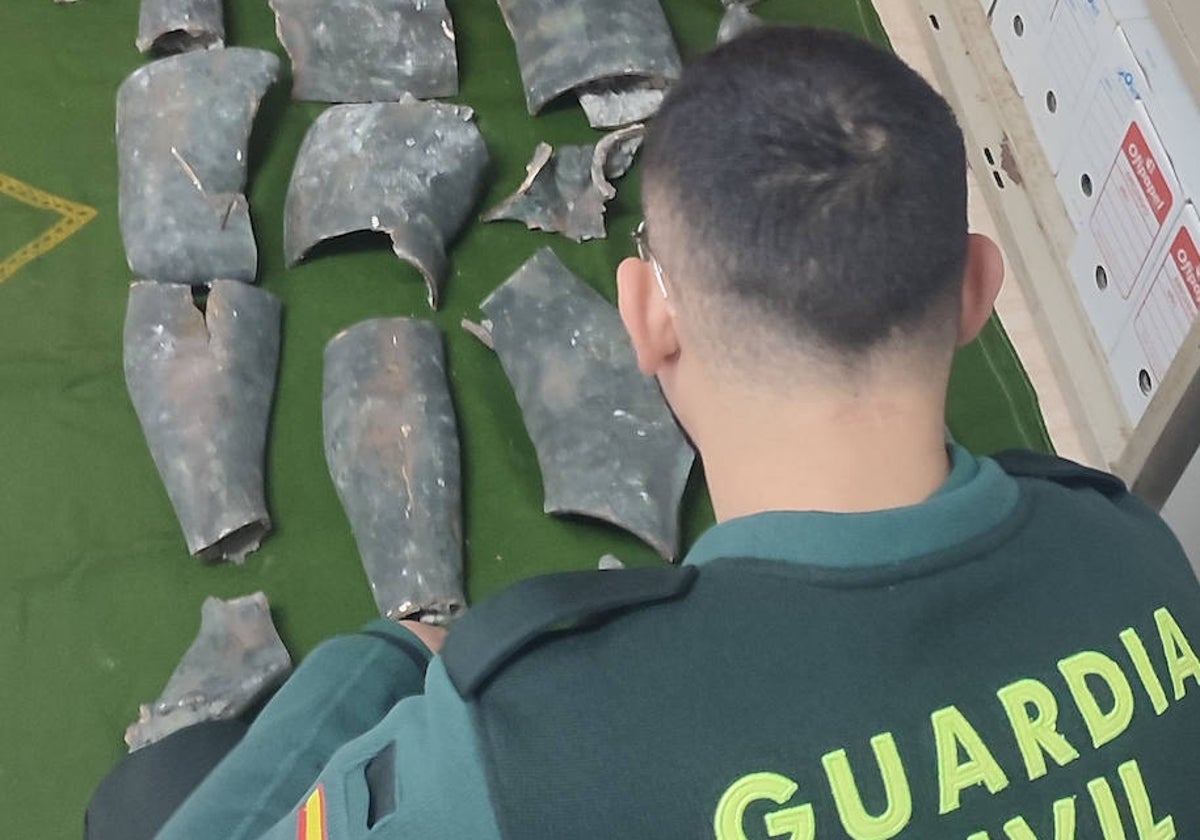 Un guardia civil examina las piezas de la estatua de Apolo de Pinedo.