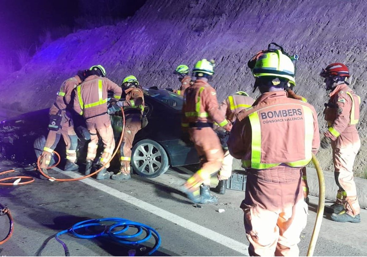 Los bomberos trabajan en el rescate de uno de los conductores atrapado tras la colisión en Navarrés.