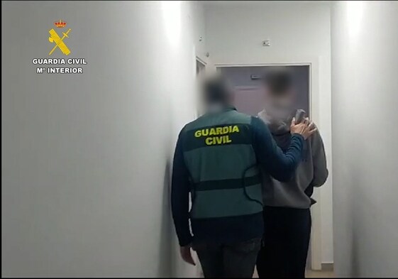 Un agente de la Guardia Civil acompaña a uno de los detenidos a dependencias de la Benemérita en Valencia.