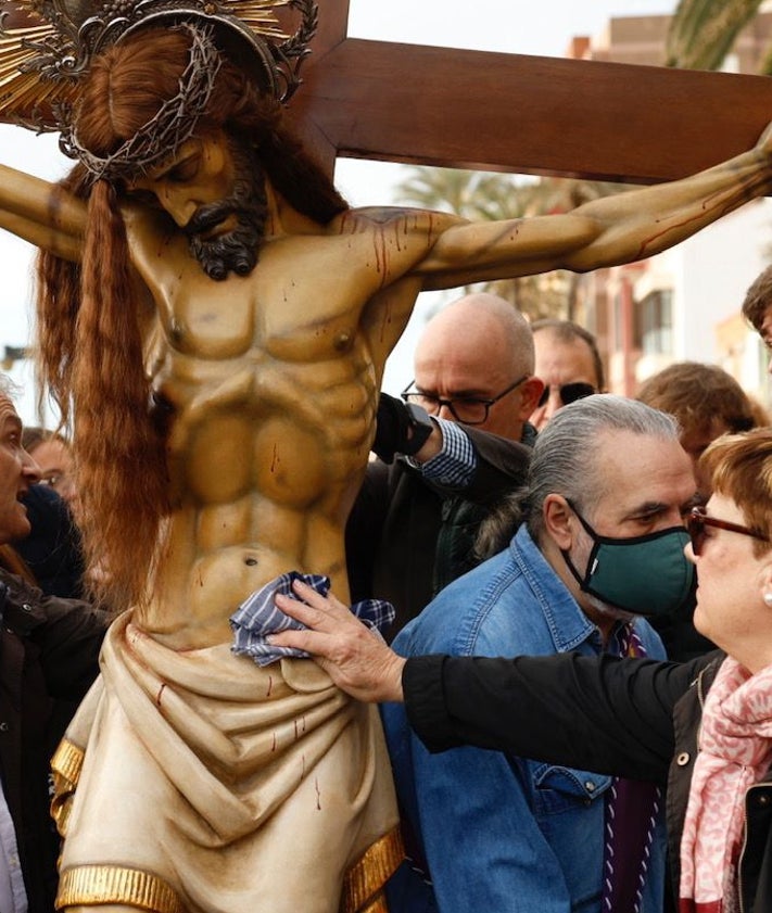 Imagen secundaria 2 - Visita a la playa y ofrenda de la corona de laurel y una devota, pasando un pañuelo al Cristo.