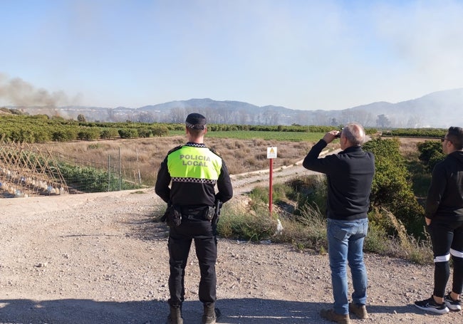 Un policía local, el alcalde y un concejal de Benaguasil observan la zona quemada.