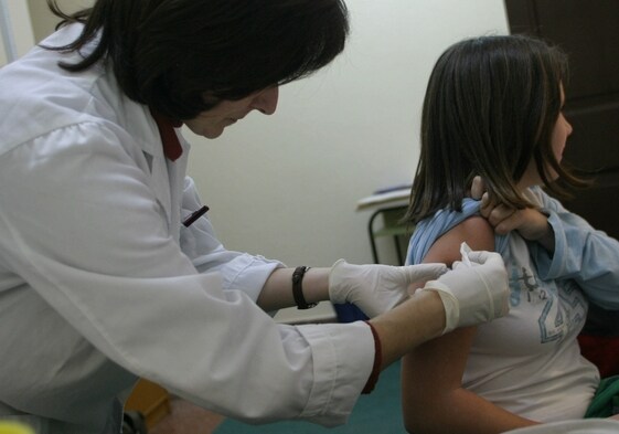 Una sanitaria vacuna a una niña contra la meningitis en un centro de salud.
