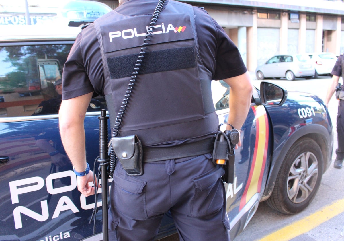 Un agente de la Policía Nacional junto a un coche patrulla.