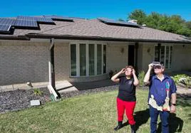 La cazadora de eclipses Leticia Ferrer y su esposo Daniel Brookshier observan el sol a través de gafas de eclipse, frente a su casa en Dallas.